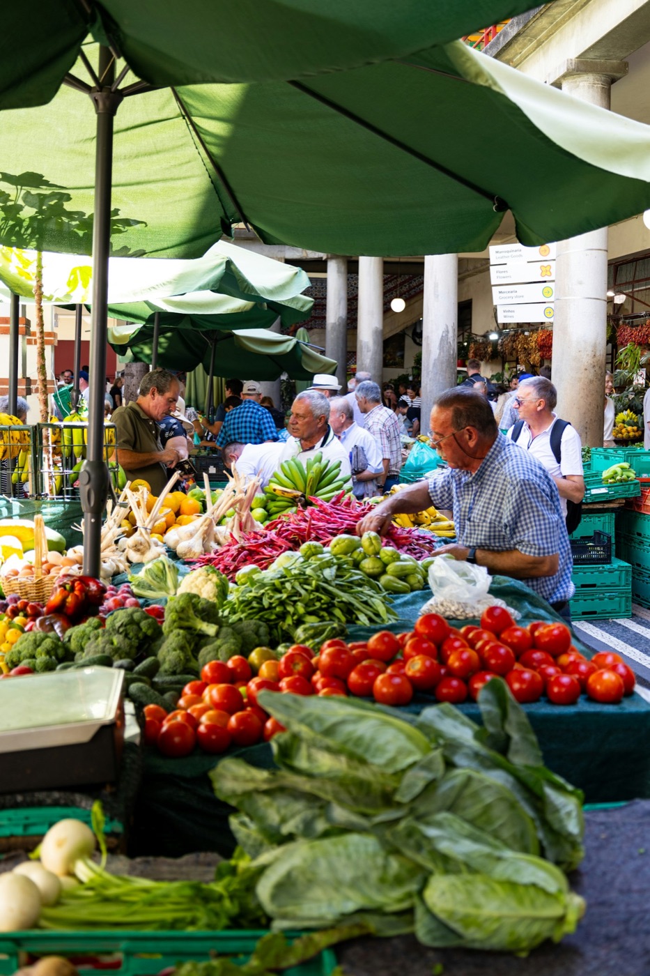 An open-air market with fruit and vegetable stalls and people shopping