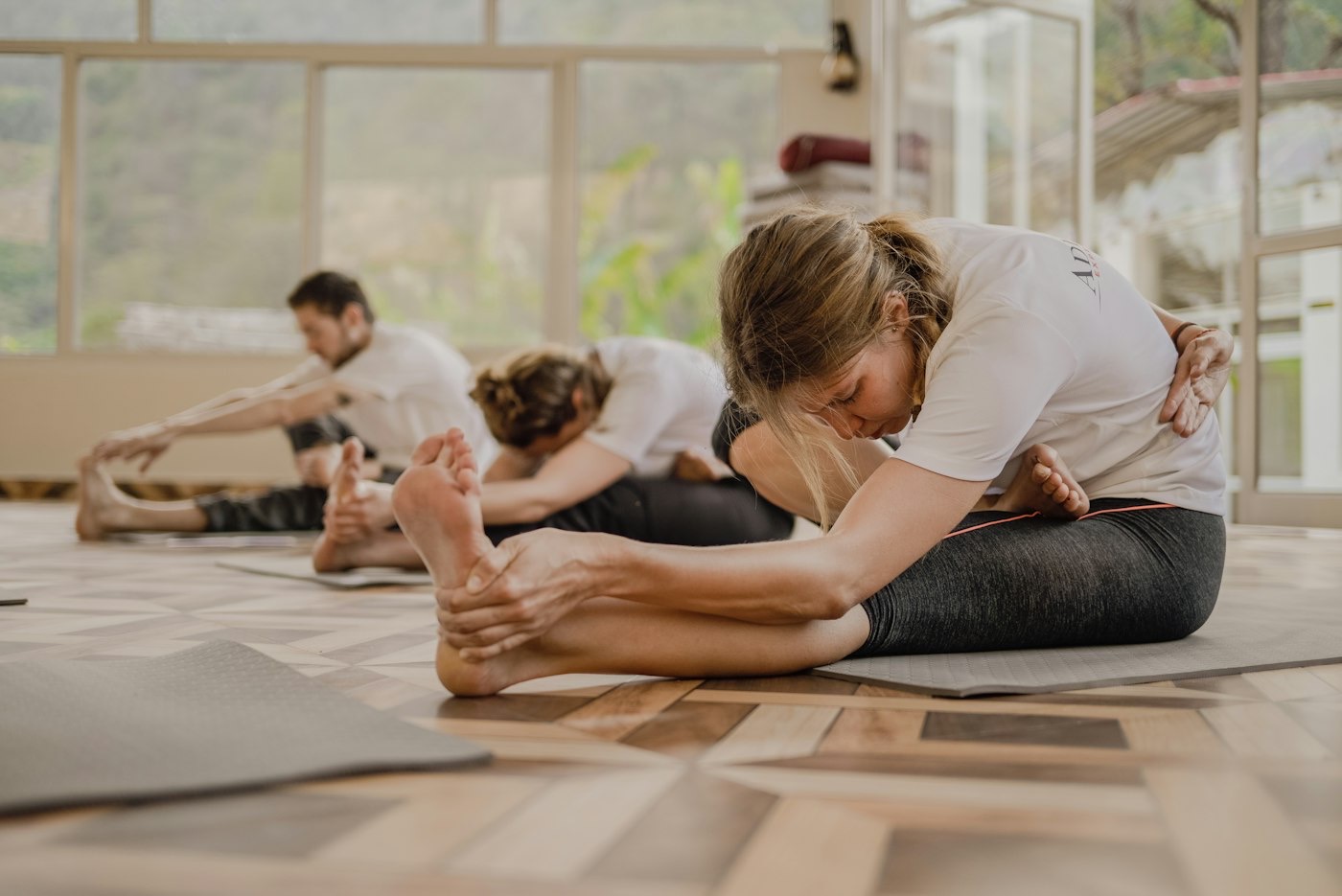 A yoga class in a bright studio, several people stretching on their mats